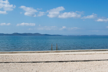 Fototapeta premium Quit and empty beach and blue sea, relaxing vacation concept with blue Adriatic sea and beach overlooking the opposite islands in Zadar, Croatia