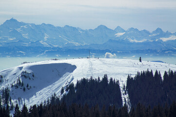 View of the Herzogenhorn in the Black Forest against the panorama of the Alps in winter.