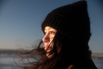Teen girl wearing a beanie hat enjoying a walk along the beach in winter sunshine - obrazy, fototapety, plakaty