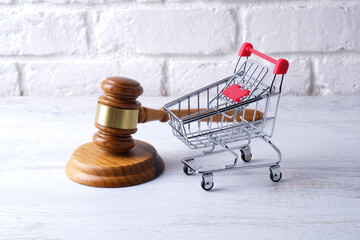grocery cart and judge gavel on white brick wall background © Alsu