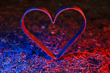 Metal heart stands in the ground and is illuminated in red and blue