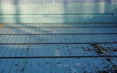 Schwimmbecken ohne Wasser mit Laubblättern am Abend im Herbst 