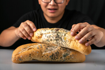 Man eating moldy dirty bread. man standing holding moldy bread. Moldy bread on blurry background. food fungus. Dirty food that is unappetizing.
