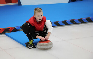 boy playing curling in a sports club - obrazy, fototapety, plakaty
