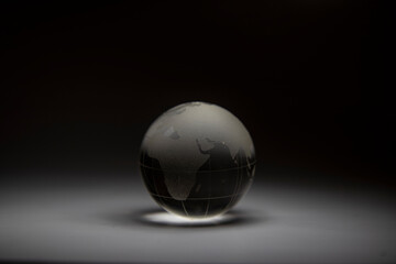 Fototapeta premium Planet Earth. Earth made of glass. Background with earth. Macro photo of figurines of the earth. Background with planet. Monochrome background. Planet of glass. Figurine of planet