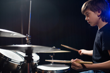 Fototapeta na wymiar A boy plays drums in a recording studio