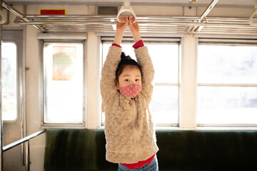 マスクを着用して電車に乗る少女