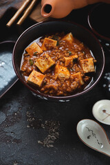Mapo tofu or chinese traditional dish made of tofu cubes, ground meat and sichuan peppercorns, vertical shot, middle close-up