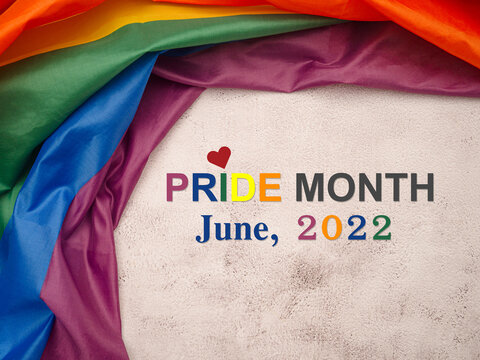 Top view of the rainbow flag or LGBT flag with text Pride month June 2022 is on a wooden table