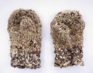 Mittens knitted from goat's down, darned with sheep's wool threads. On a light background - obrazy, fototapety, plakaty