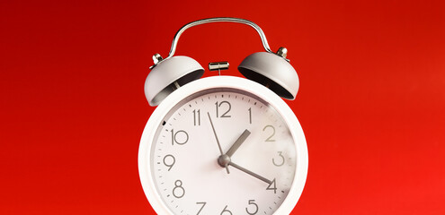 White alarm clock on red background