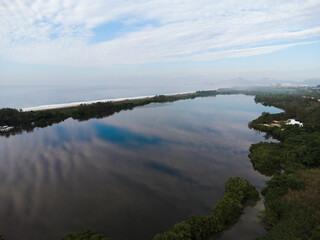 Aerial view of Reserva beach and Marapendi lagoon. In the background, the hills of Recreio dos Bandeirantes, in Rio de Janeiro, Brazil. Dawn. Sunny day with some clouds. Drone photo