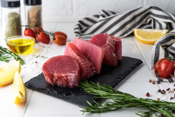 Fresh tuna fillet steaks with spices, vegetables and herbs on a plate. Preparing tuna for baking. High quality photo