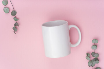 Obraz na płótnie Canvas Mockup white coffe cup or mug on a pink background with copy space. Blank template for your design, branding, business. Real photo. Eucalyptus branches. Flat lay nobody