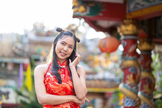 Asian beautiful woman wearing red traditional Chinese cheongsam decoration using mobile phone video chatting for Chinese new year theme.