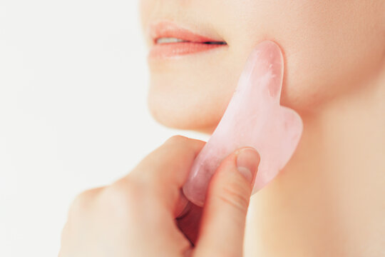 The girl drives stone massager over her cheekbones.