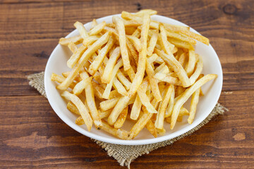 Potato sticks close up in white dish on an wooden table, snack food