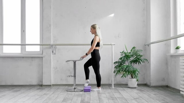 Graceful female training. Feet exercise. Blonde woman warming up. Sport and fitness. Young sportswoman doing morning fitness routine indoors. 4K, UHD