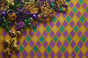 Frame of Mardi Gras Mask and colorful Mardi Gras Beads on diamond shaped background - obrazy, fototapety, plakaty