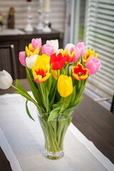 bouquet of colorful tulips stands on a table in a vase