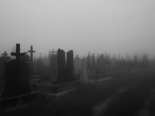 Dark ancient cemetery in the fog. Crosses and graves in the old abandoned cemetery. Place of burial. Black White photo.