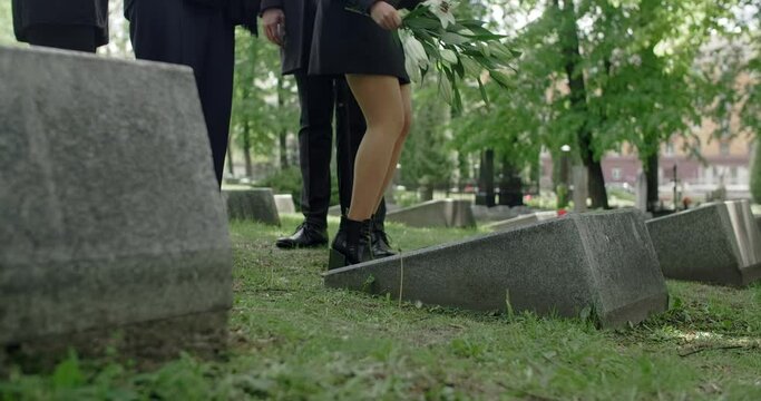 Latin woman lays flowers to the grave stone and strokes it. Griving at the cemetery, 4k 60p Prores