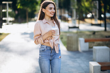 Obraz premium Young woman drinking coffee in park