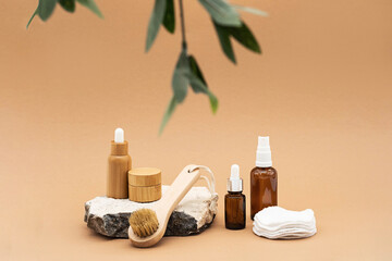 Naklejka na ściany i meble Blank amber glass and bamboo essential oil bottles with pipette, glass spray bottle and bamboo jar on natural stone podium. Organic spa cosmetic beauty product mock up.