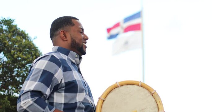 dominican man playing tambora merengue with dominican flag