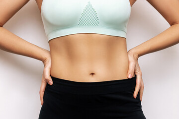 Fototapeta na wymiar Cropped shot of a young slender woman with toned stomach with abs isolated on a white background. Result of fitness, diet, healthy lifestyle. Female belly after a lot of training. Lines and six-packs