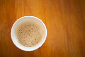 Coffee cup top view with bubble on wooden table background.
