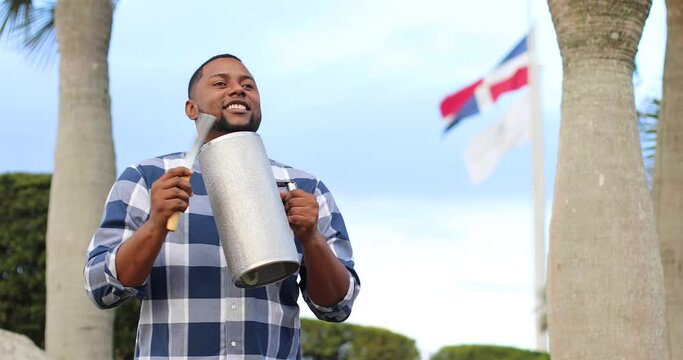 dominican man playing tambora guira with dominican flag