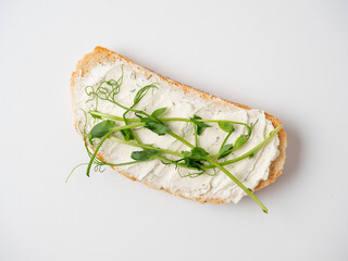 Close-up of a slice of bread spread with cottage cheese and decorated with micro greenery isolated...