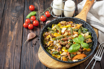 Seafood ragout, healthy mediterranean dinner. Seafood shrimps, calamari, cuttlefish stewed with vegetables and garlic sauce in a frying pan, on an wooden table. Copy space.