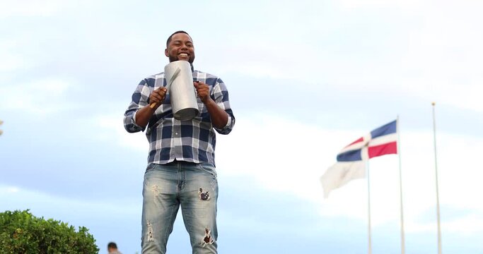 dominican man playing tambora guira with dominican flag