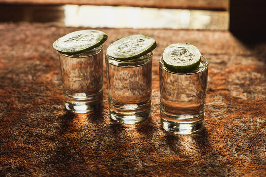 Glasses with Georgian grape vodka chacha and cucumber for a snack - a traditional strong alcoholic drink for a feast