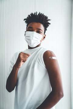 African American teenager showing COVID-19 vaccine bandage merrily in concept of coronavirus vaccination program to vaccinate citizen .