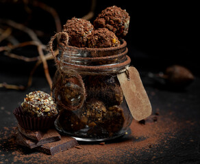 
Homemade chocolate truffles with cocoa powder in a glass jar on a dark background