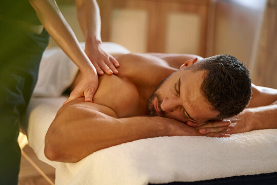 Close-up of a masseuse giving a massage to a young man in a spa salon