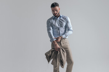 cool fashion model adjusting sleeve and holding jacket