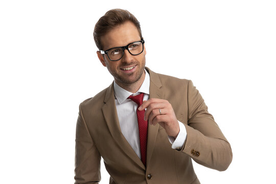 cool businessman looking away, wearing eyeglasses and fixing his tie