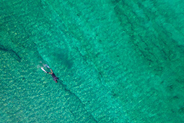 Spearfishing scuba diver in tropical exotic sea, ocean turquoise clear water. Man swimming hunting exotic fish, poaching. Top view. Aerial, drone, copter view.