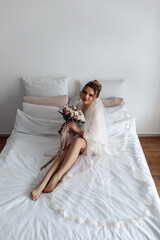 Fototapeta na wymiar The bride on the bed holds a wedding bouquet. Bride morning. Beautiful bouquet of roses.