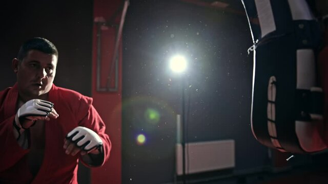 Taekwondo practitioner in a red kimono is training in a gym