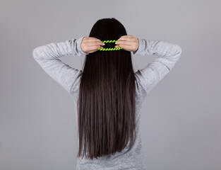 Young woman tie hair. Gray background.