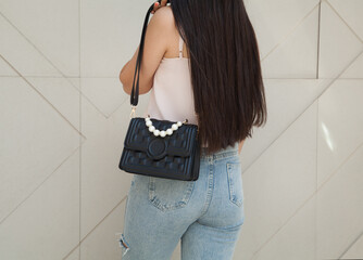 Young woman holding luxury handbag, and wearing trendy outfit. Fashion concept.