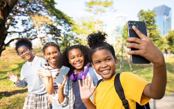 Group of friends taking pictures via smartphone. They have a bright and friendly smile. Concepts of relationship building and leisure in the park