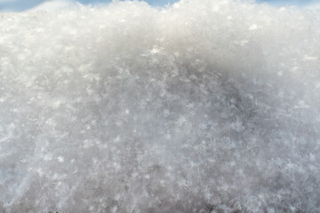 Snowflakes glow in the sun, on fluffy snow, on a frosty winter day. Copy space. Abstract background. 