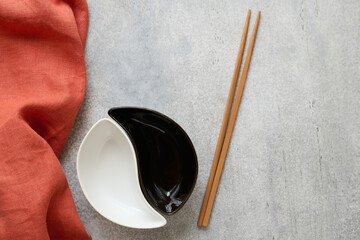 2 ceramic bowls, bamboo chopsticks, and a linen napkin on a concrete table with space for text - 480746300