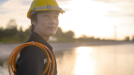 A male engineer wearing a protective helmet at sunset..